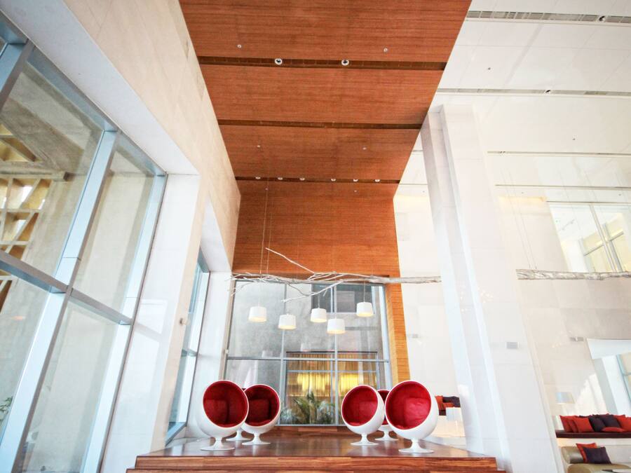 Un intérieur moderne avec des escaliers en bois menant à un espace détente agrémenté de chaises rouges.