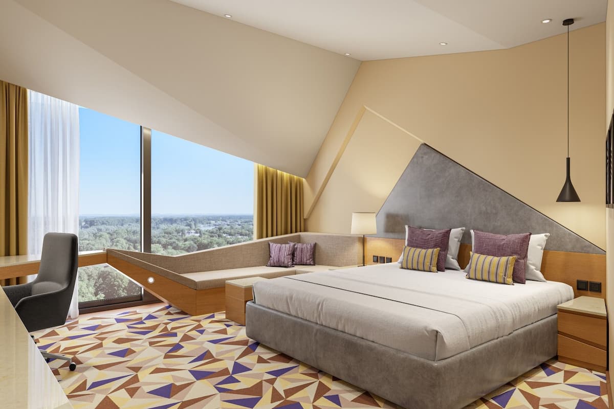 A modern hotel room with a large bed, a desk, and a view of the city.