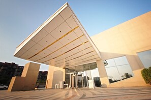 A modern building with a large overhang, glass entrance, and a paved entrance area. - Vivanta New Delhi, Dwarka (New Delhi)