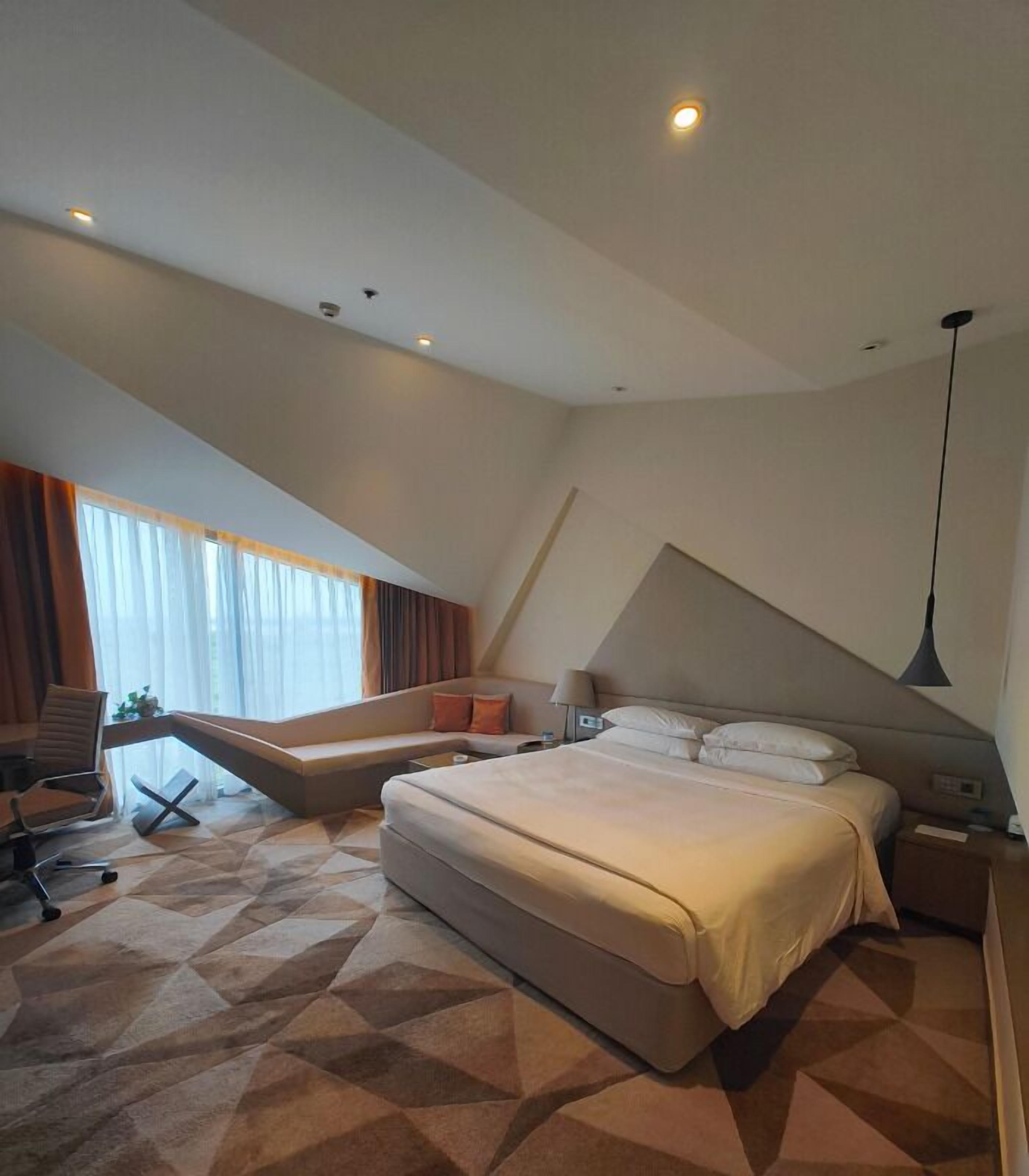 Een moderne hotelkamer met een groot bed, een bureau en een stoel.