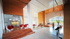 A spacious lobby with a wooden staircase, modern seating, and a large chandelier. - Vivanta New Delhi, Dwarka (New Delhi)