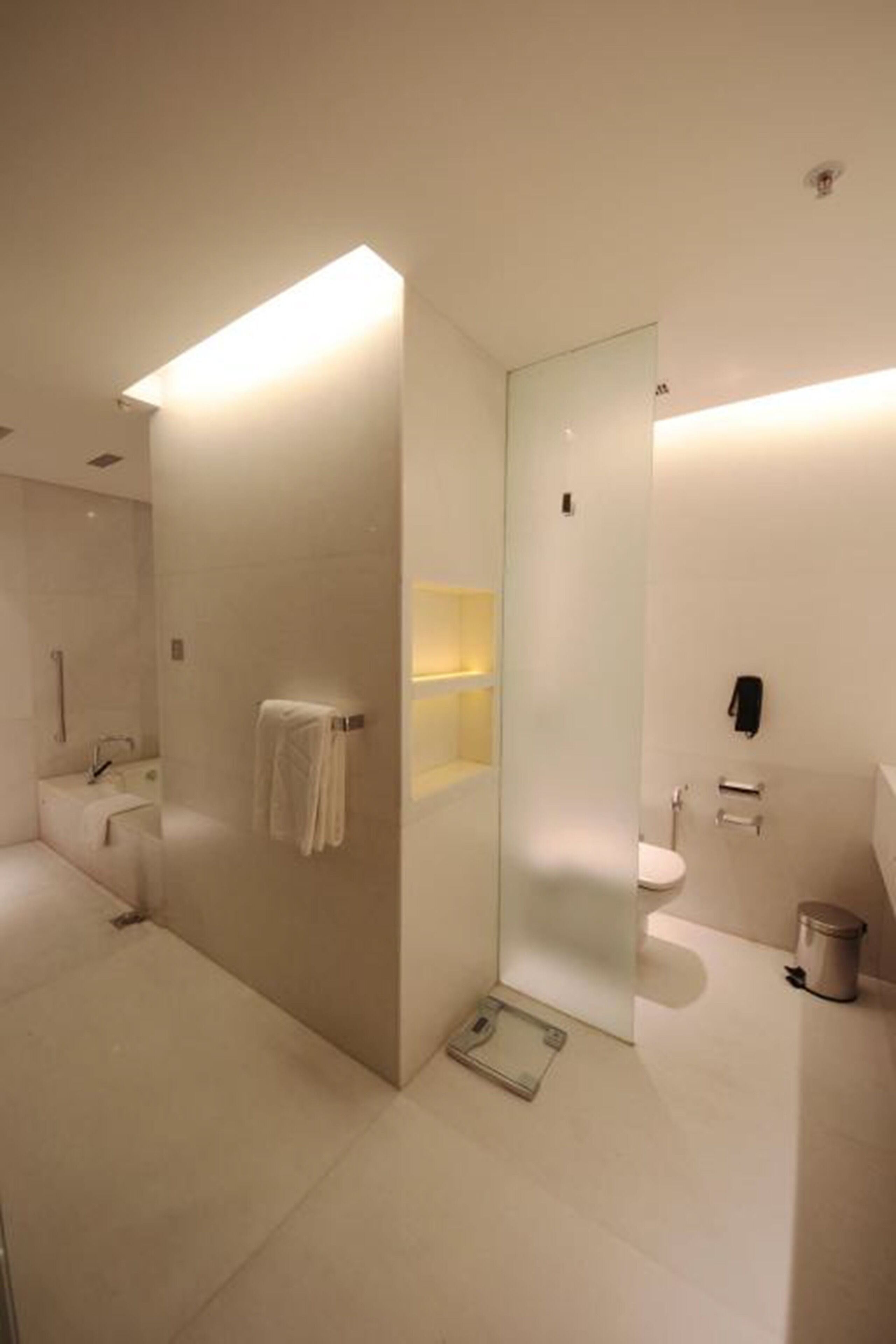 Un baño moderno con separador de vidrio, inodoro, lavamanos y zona de ducha.