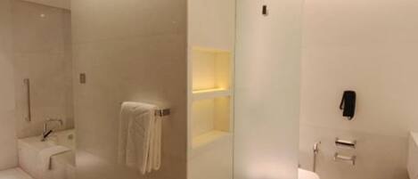 Un baño moderno con separador de vidrio, inodoro, lavamanos y zona de ducha.