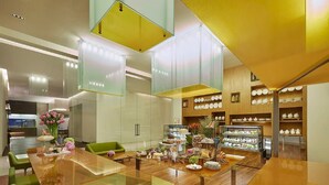 A modern dining area with a glass-top table, green chairs, and a variety of food displays. - Vivanta New Delhi, Dwarka (New Delhi)