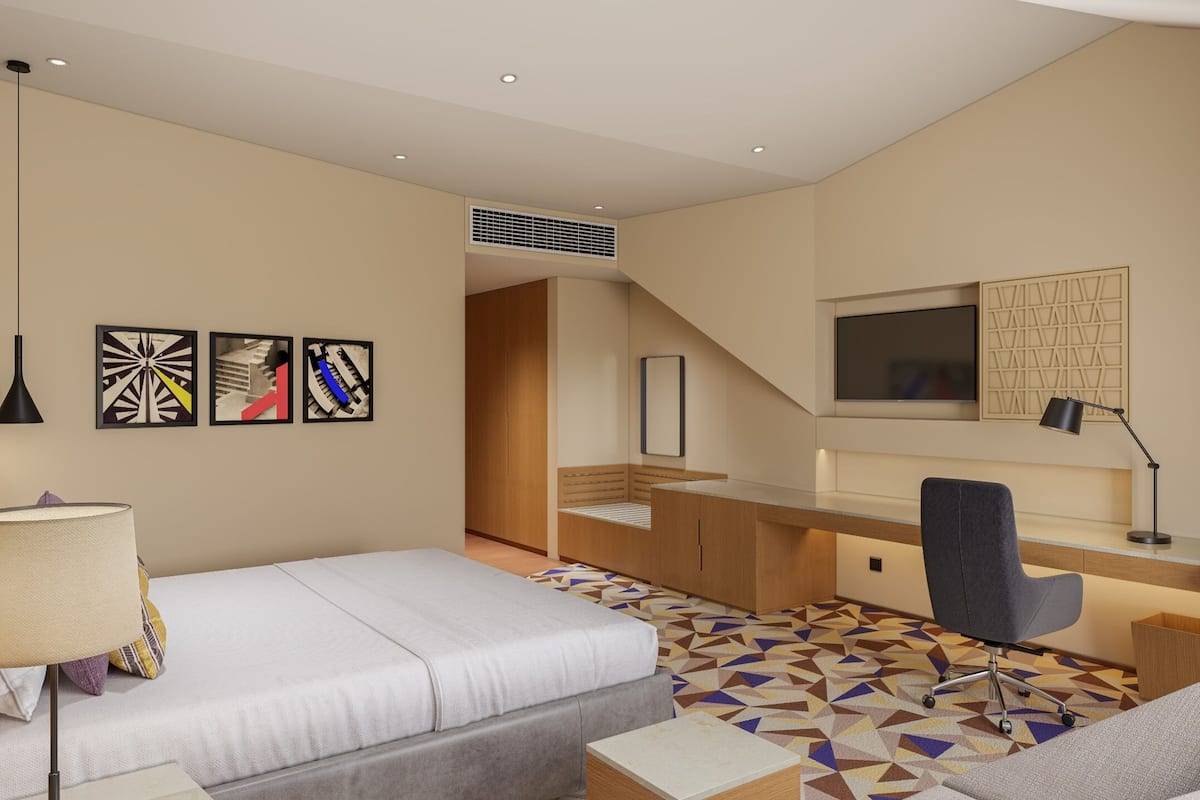 A modern hotel room with a bed, desk, chair, and a TV.