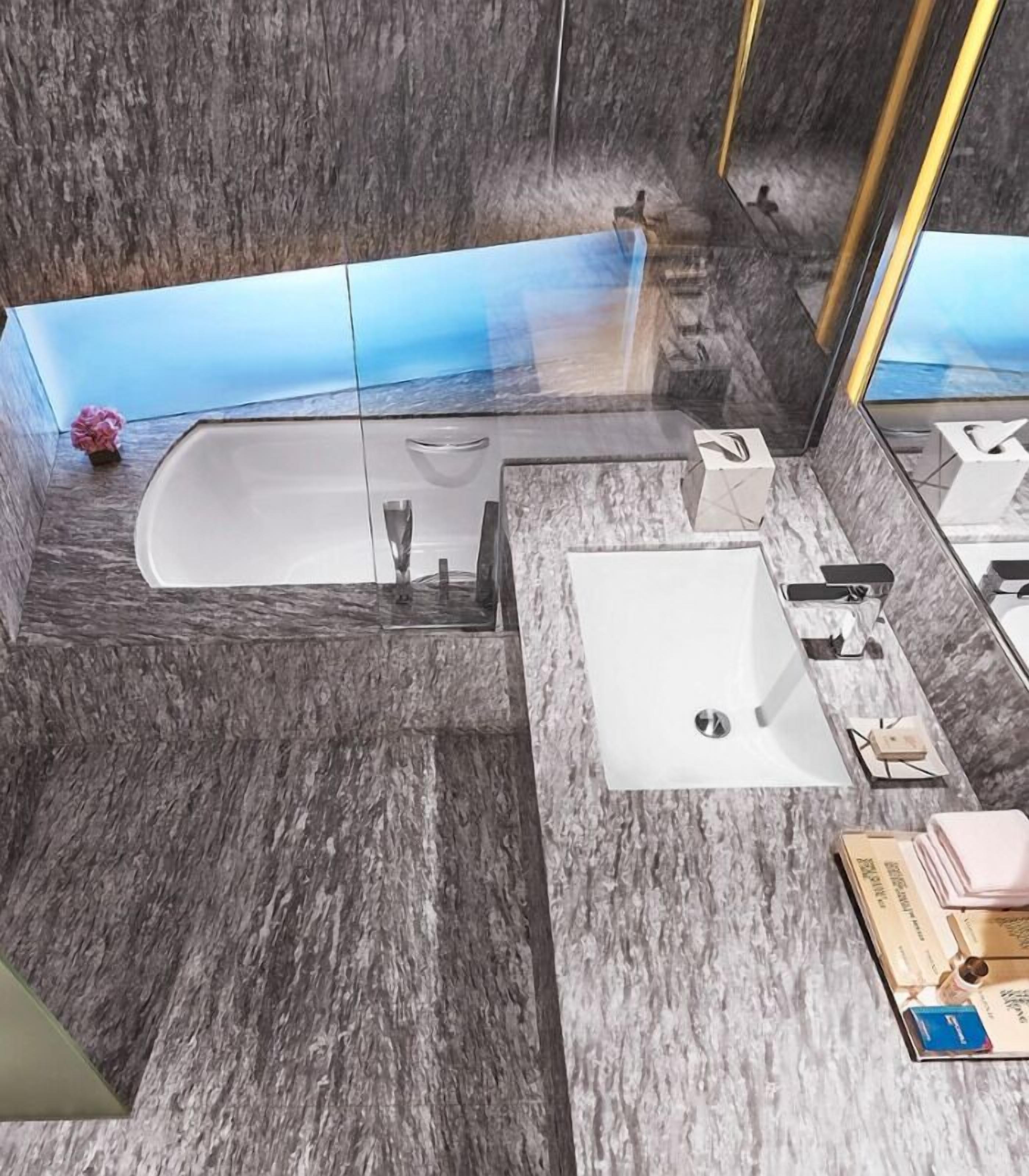 A modern bathroom with a marble floor, a bathtub, a sink, and a large mirror.