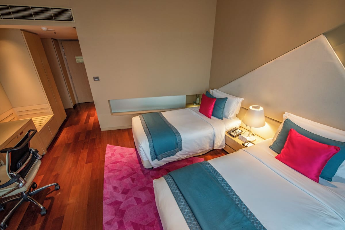 A hotel room with two beds, a desk, and a chair.