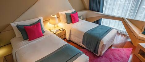Una habitación de hotel con dos camas, cada una con un cojín y una mesita de noche con una lámpara.
