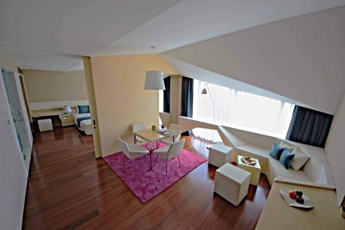 A modern living room with a dining area, a sofa, and a small kitchen.