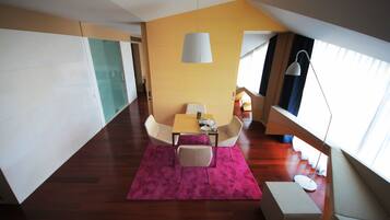 A modern dining area with a table and chairs, a pink rug, and a large window with curtains.