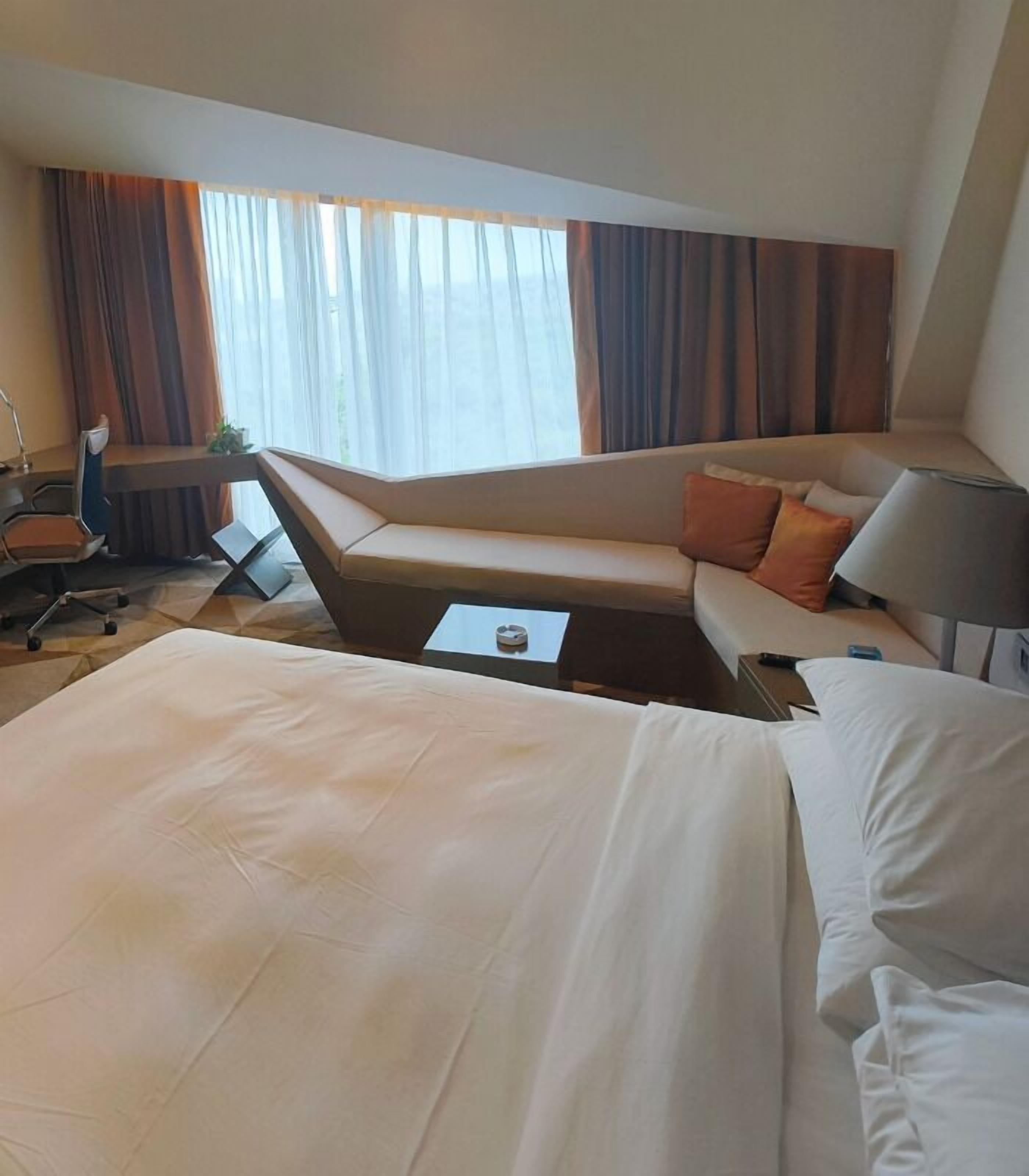 Una habitación de hotel con una cama grande, un sofá, un escritorio y una silla.