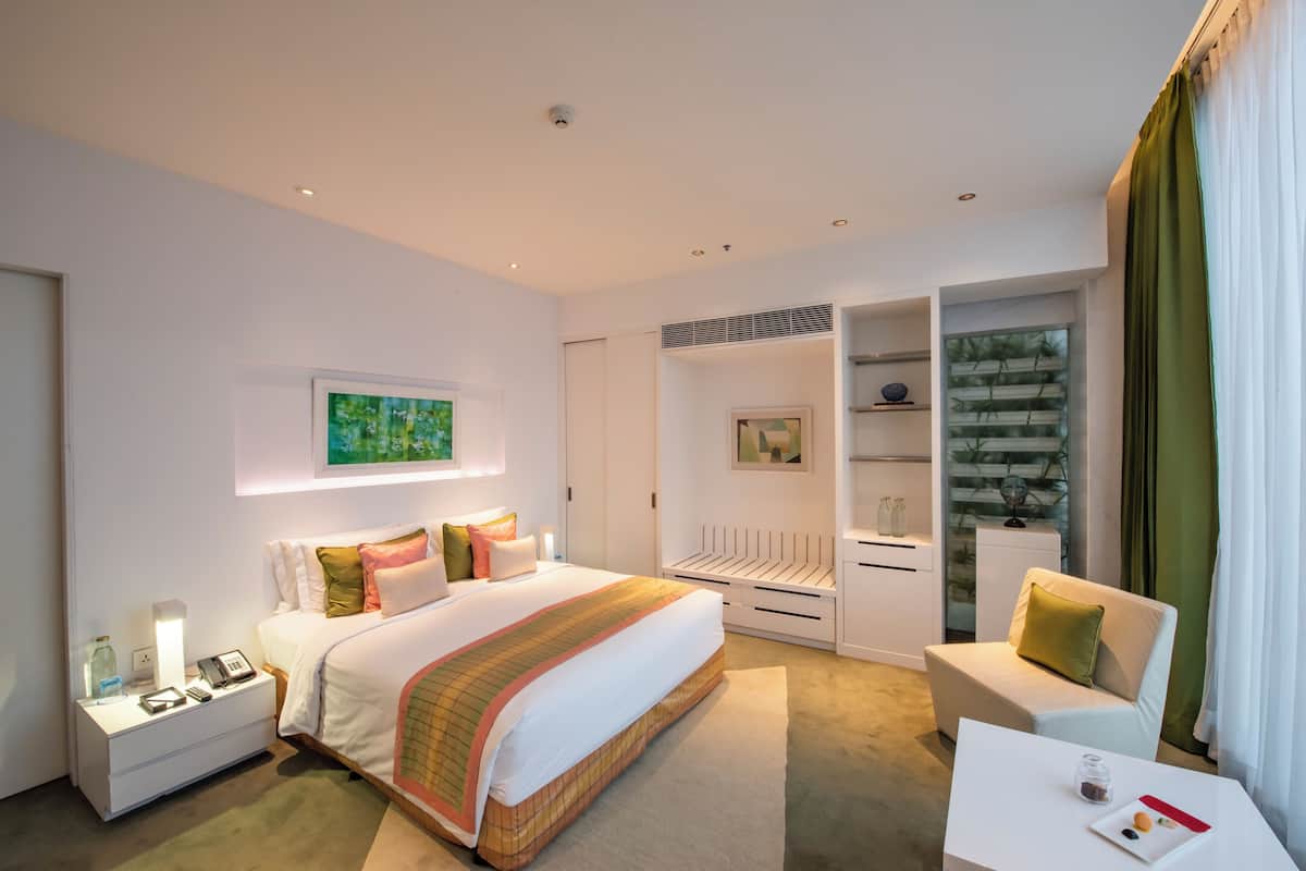 A modern hotel room with a large bed, bedside tables, a desk, and a chair.