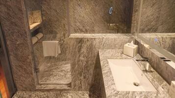 A modern bathroom with a marble sink, a towel rack, and a mirror.