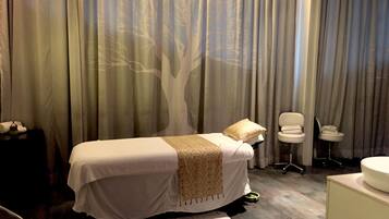A hotel room with a bed, a chair, a small table, and a bathroom area.