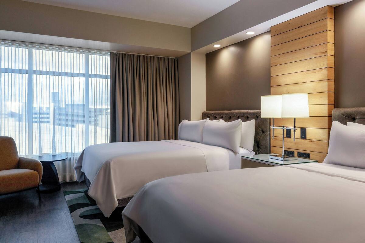 A hotel room with two beds, a sofa, a small table, and a lamp.