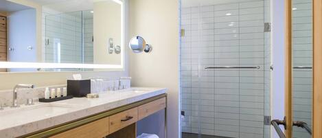 A modern bathroom with a large mirror, a sink, and a glass-enclosed shower.