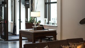 Un intérieur moderne avec un canapé, une table et une lampe. De grandes fenêtres et un lustre complètent l’ensemble.