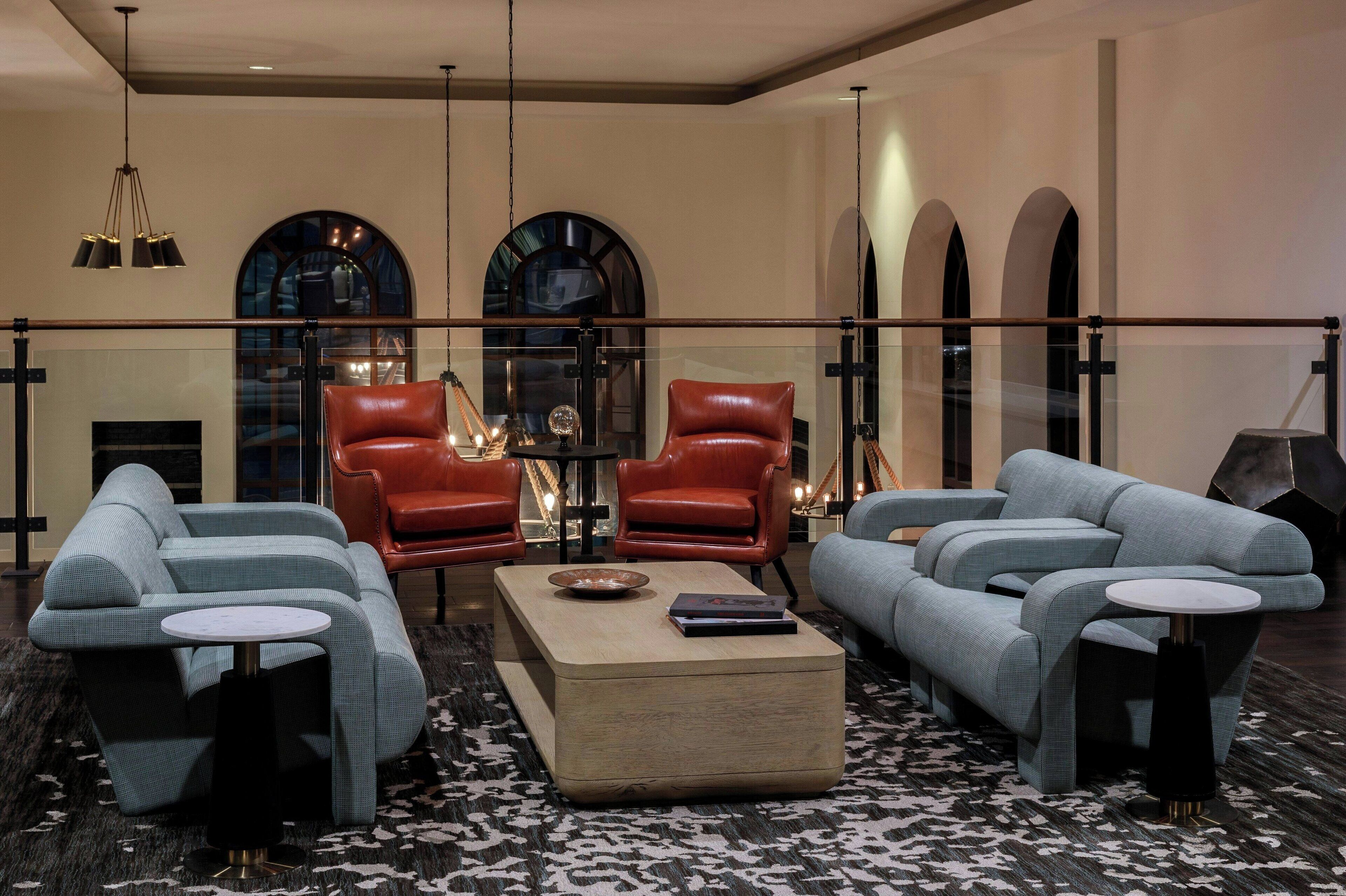 A spacious living area with a modern sofa set, leather armchairs, and a coffee table.