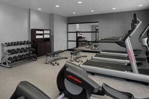 Une salle de sport équipée de tapis de course, d’haltères et d’appareils de musculation.