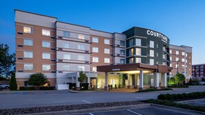 A Courtyard by Marriott hotel with a modern design, featuring multiple floors, a central entrance, and a parking area.