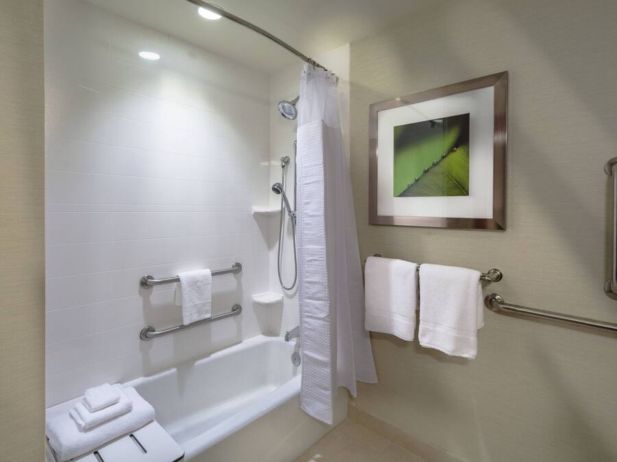 Un baño moderno con bañera, ducha y barras de apoyo.