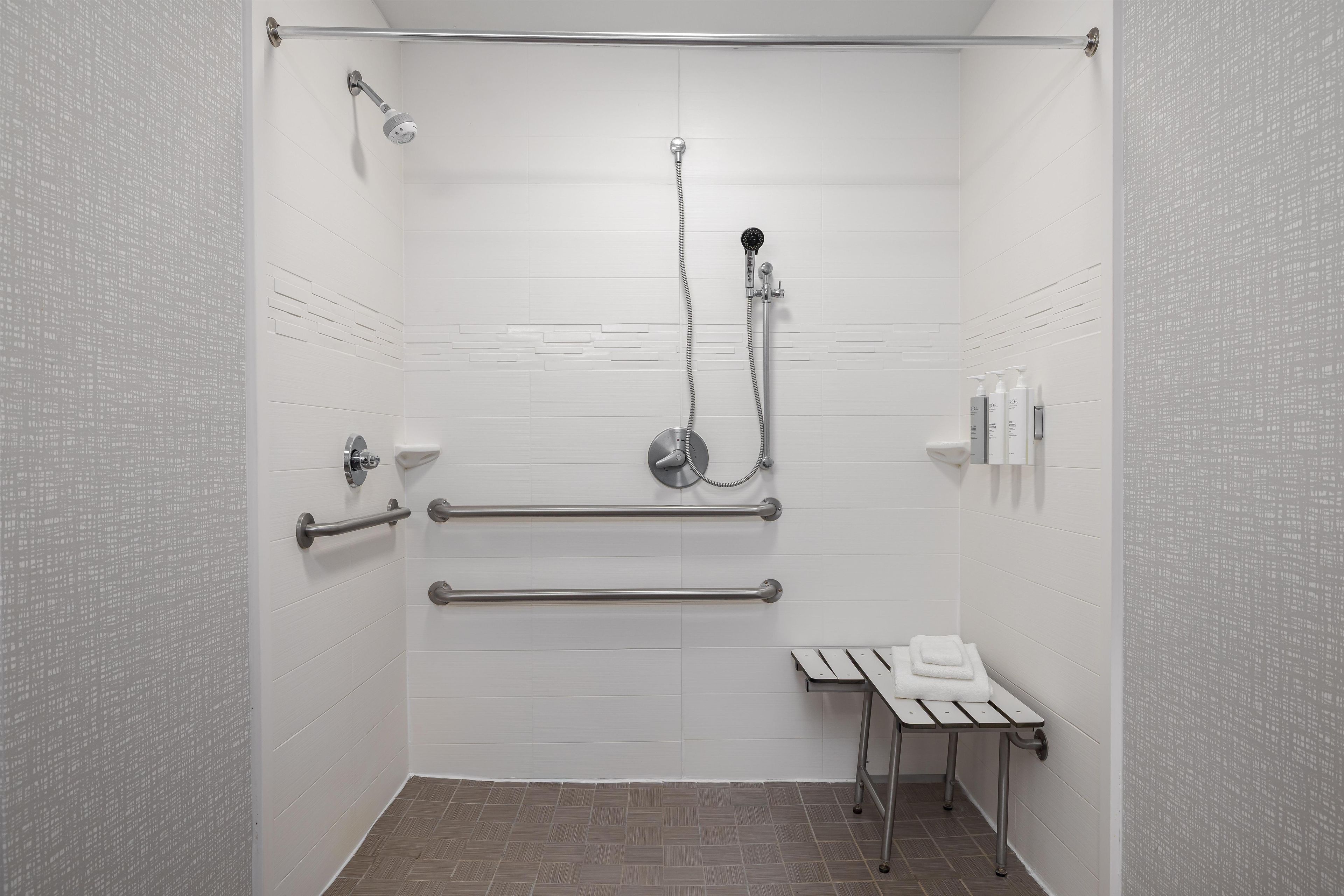 A shower stall with a handheld showerhead, a handheld shower attachment, and a handheld shower hose.