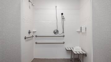 A shower stall with a handheld showerhead, a handheld shower attachment, and a handheld shower hose.