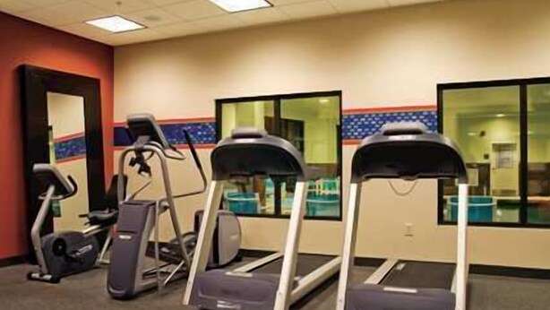 Un gimnasio con cintas de correr y equipo de ejercicio.