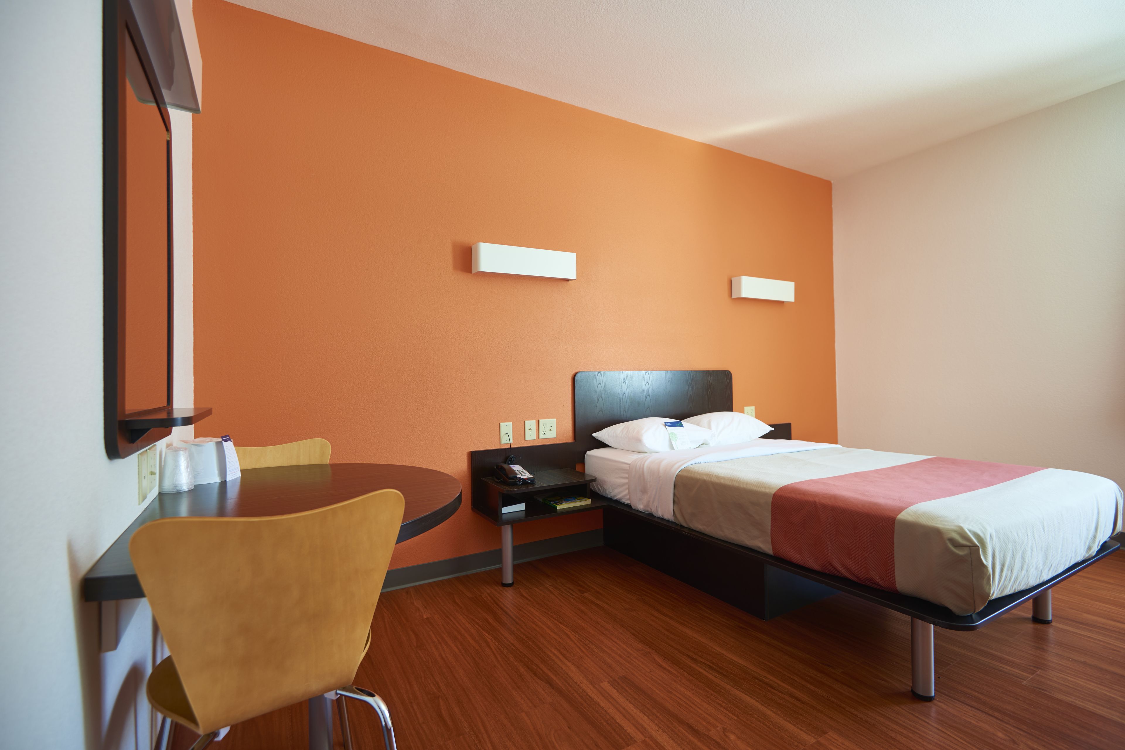 A hotel room with a bed, a desk, a chair, and a nightstand.