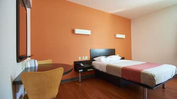 A hotel room with a bed, a desk, a chair, and a nightstand.