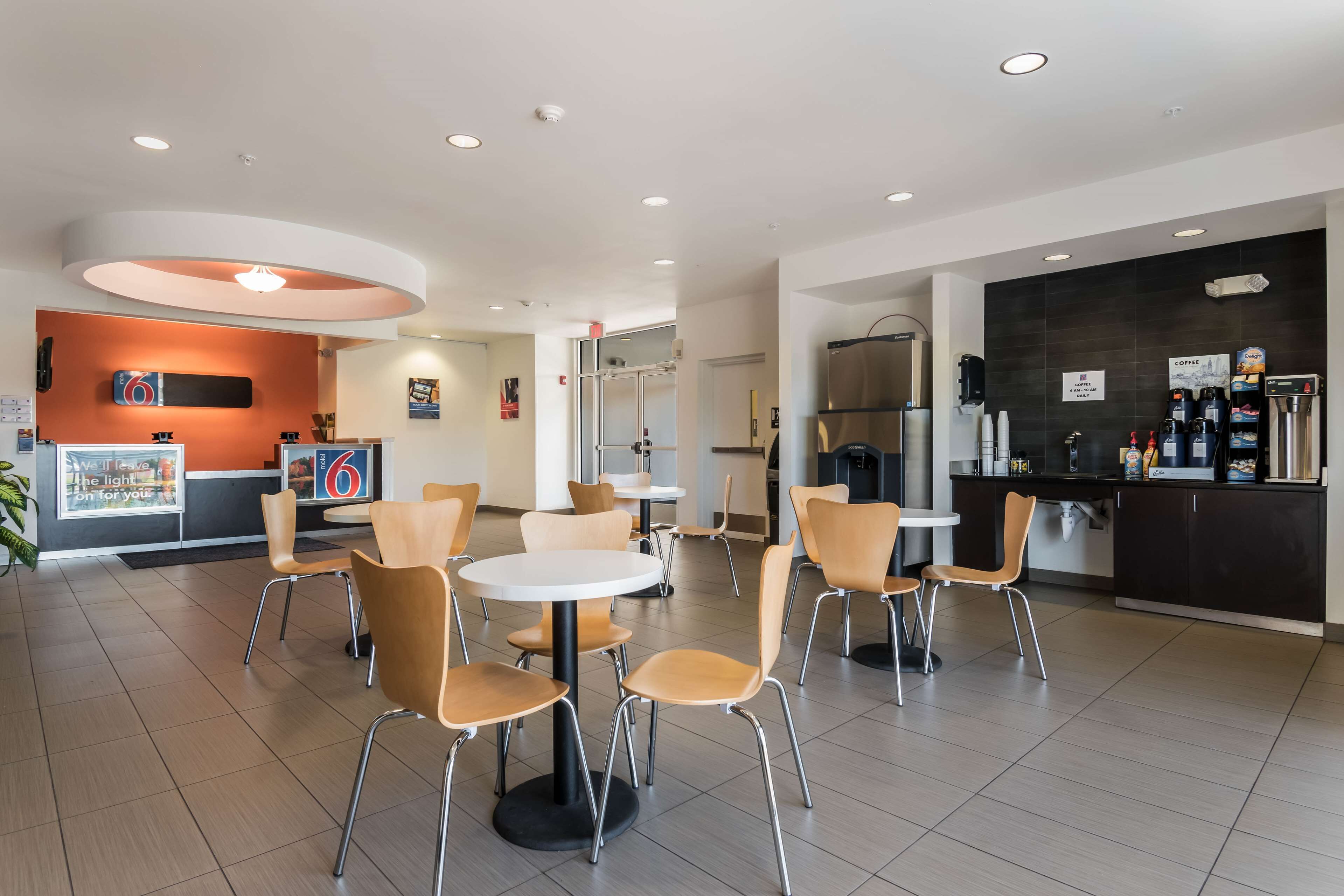 A modern cafe with round tables and chairs, a coffee bar, and a digital clock.