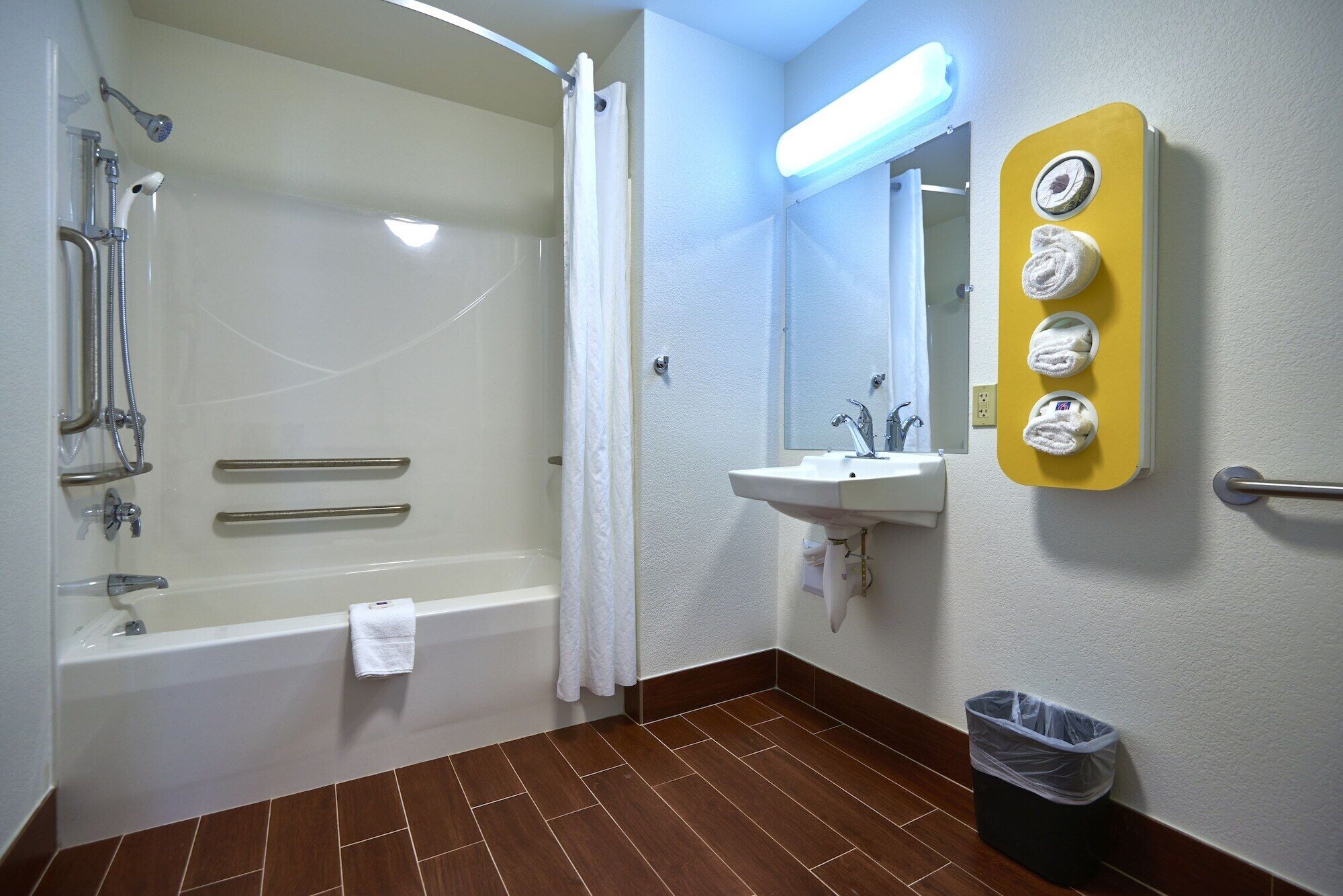 Een badkamer met een badkuip, douche, wastafel en een handdoekrek met handdoeken.