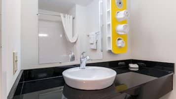 A bathroom with a white sink, black countertop, and a mirror with a yellow towel rack.