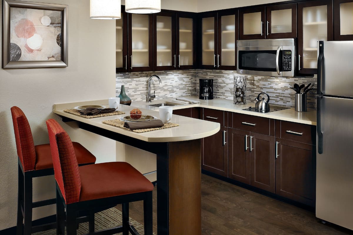 A modern kitchen with dark wooden cabinets, stainless steel appliances, and a central island with seating.