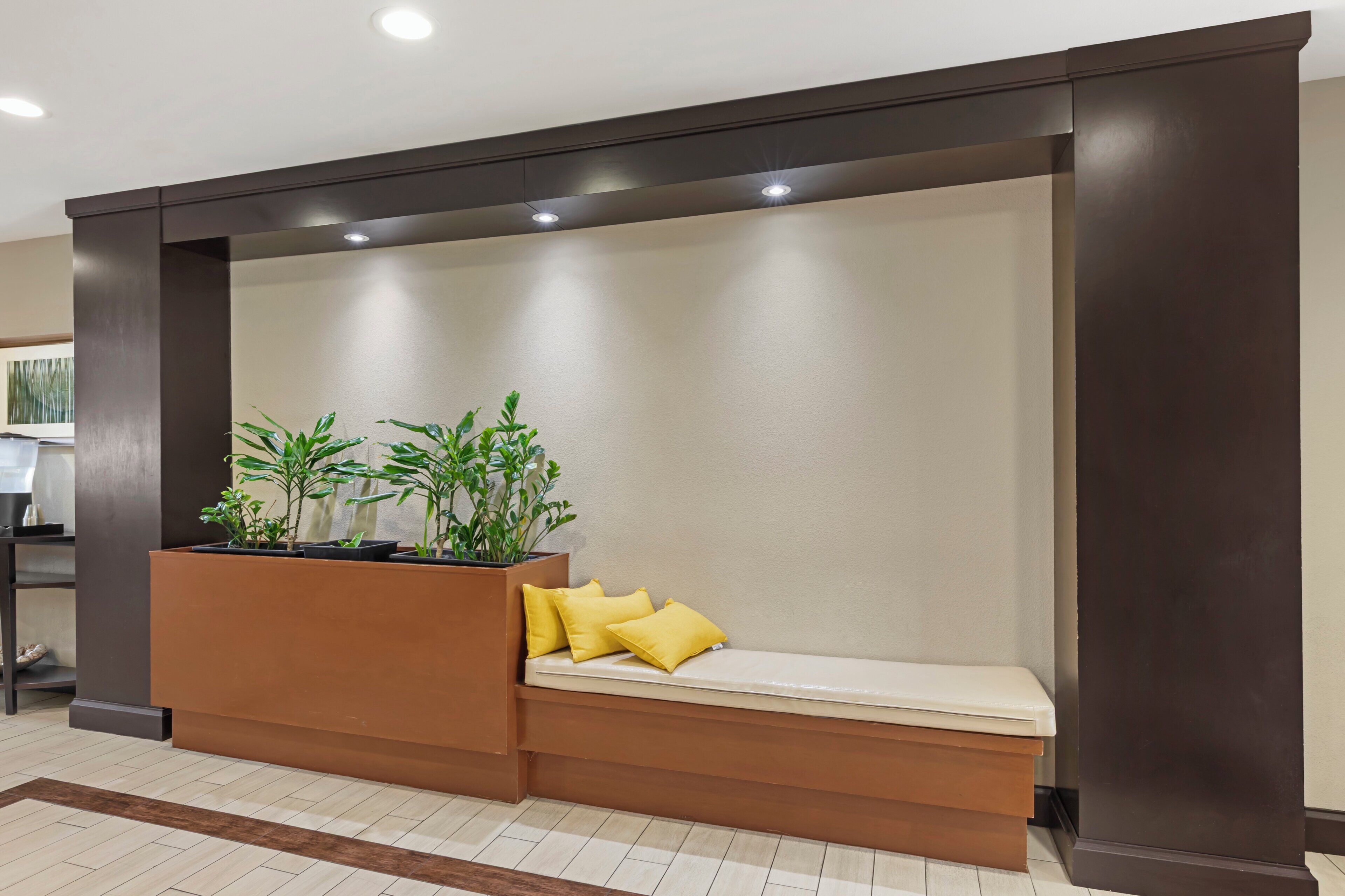 A reception area with a bench, potted plants, and a wall-mounted light fixture.