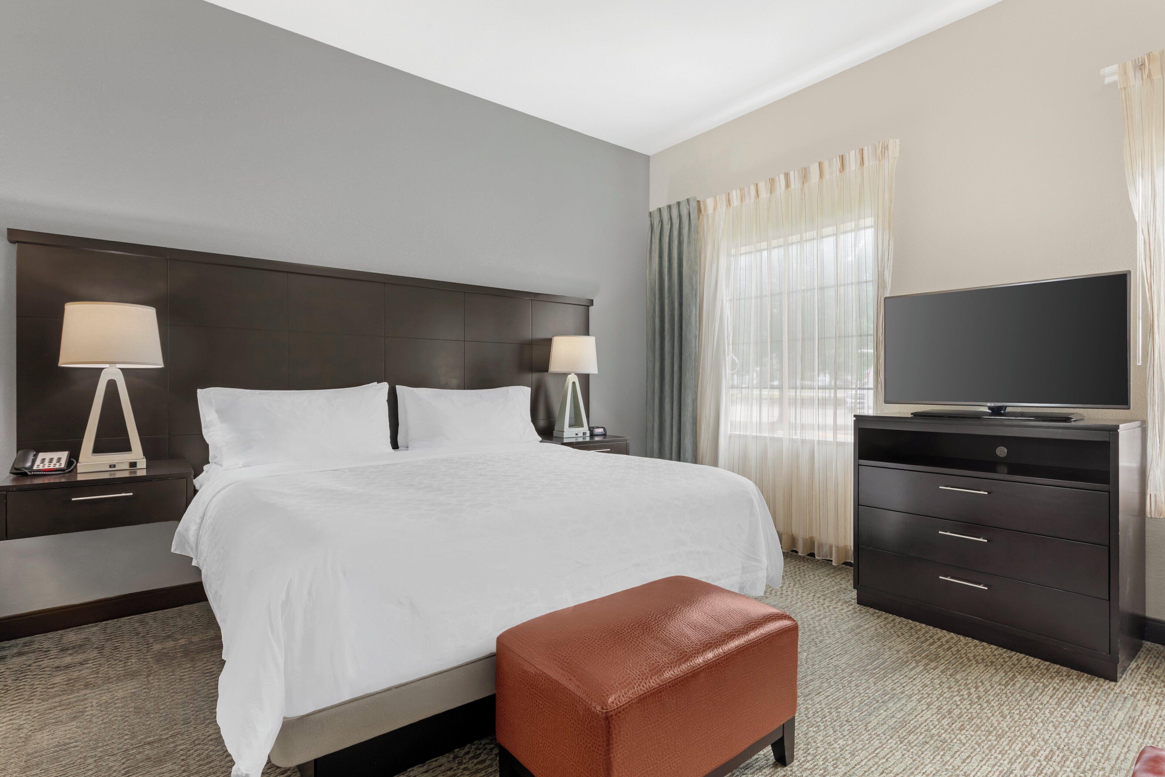 A hotel room with a bed, a television, a desk, and a chair.