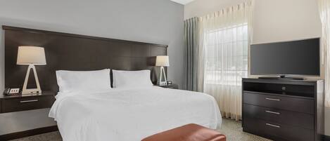 A hotel room with a bed, a television, a desk, and a chair.