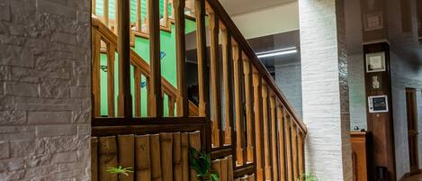 Una escalera con barandilla de madera y pared de ladrillo.
