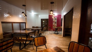 A restaurant with wooden tables and chairs, hanging pendant lights, and a herringbone floor pattern.