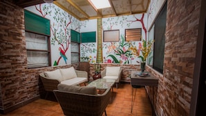 A cozy room with wicker furniture, a tiled floor, and a mural of birds and flowers on the wall.