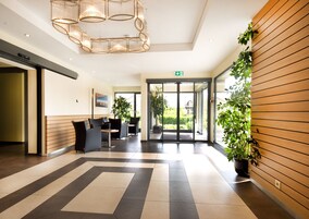 Un vestíbulo de hotel con diseño moderno, que incluye un mostrador de recepción, zona de estar y un amplio ventanal hacia el exterior.