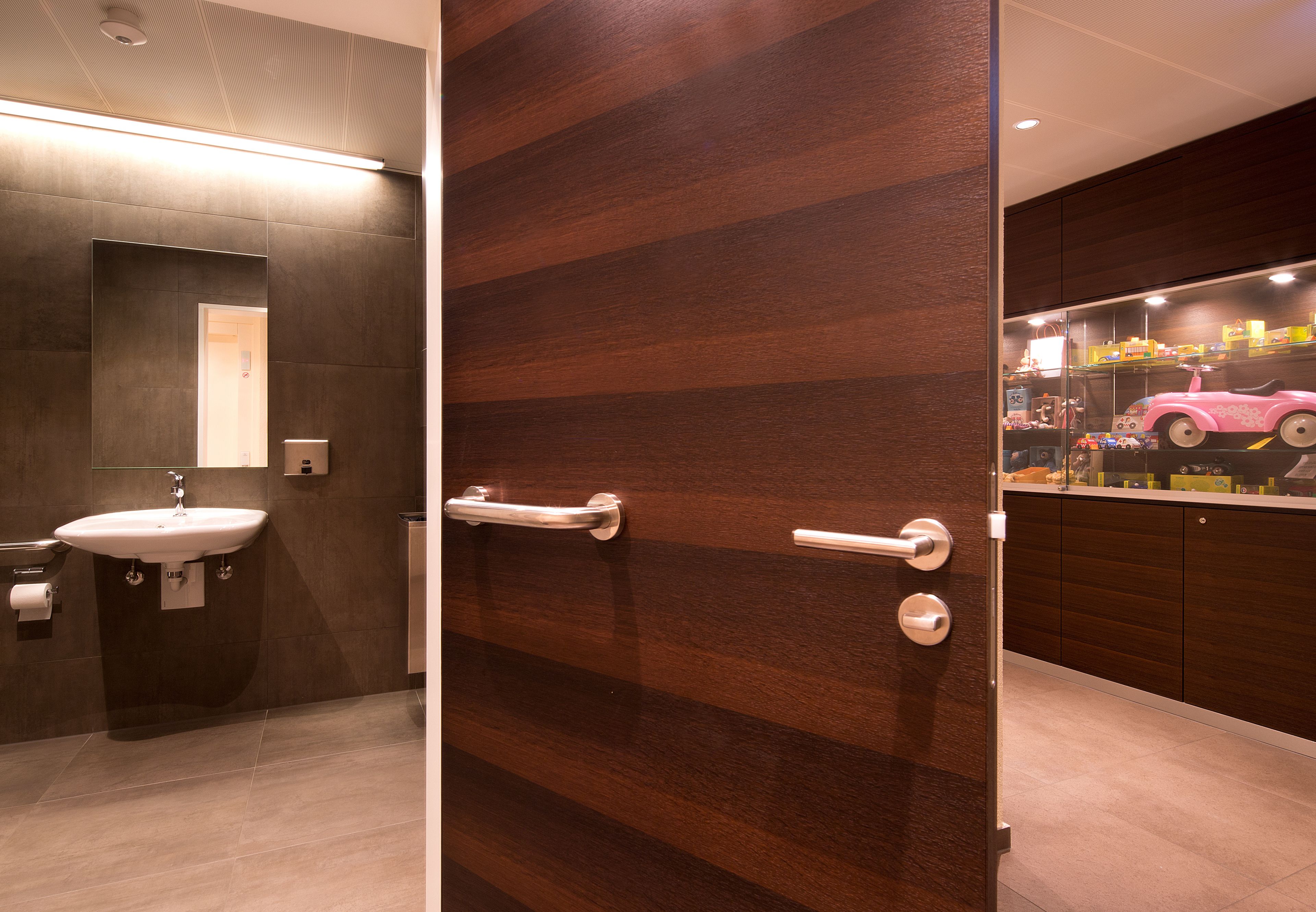 A modern bathroom with a wooden door, a sink, and a mirror.