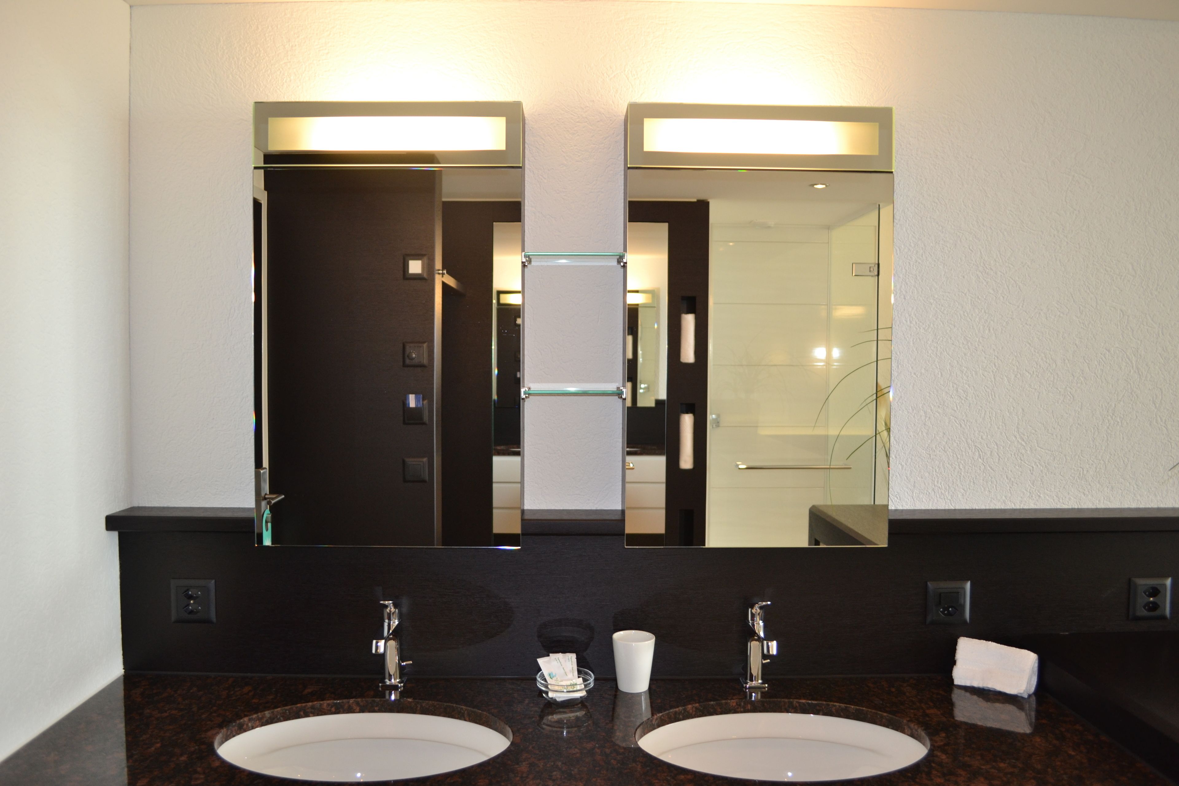 Un baño con dos lavamanos, un espejo grande y un perchero para toallas.