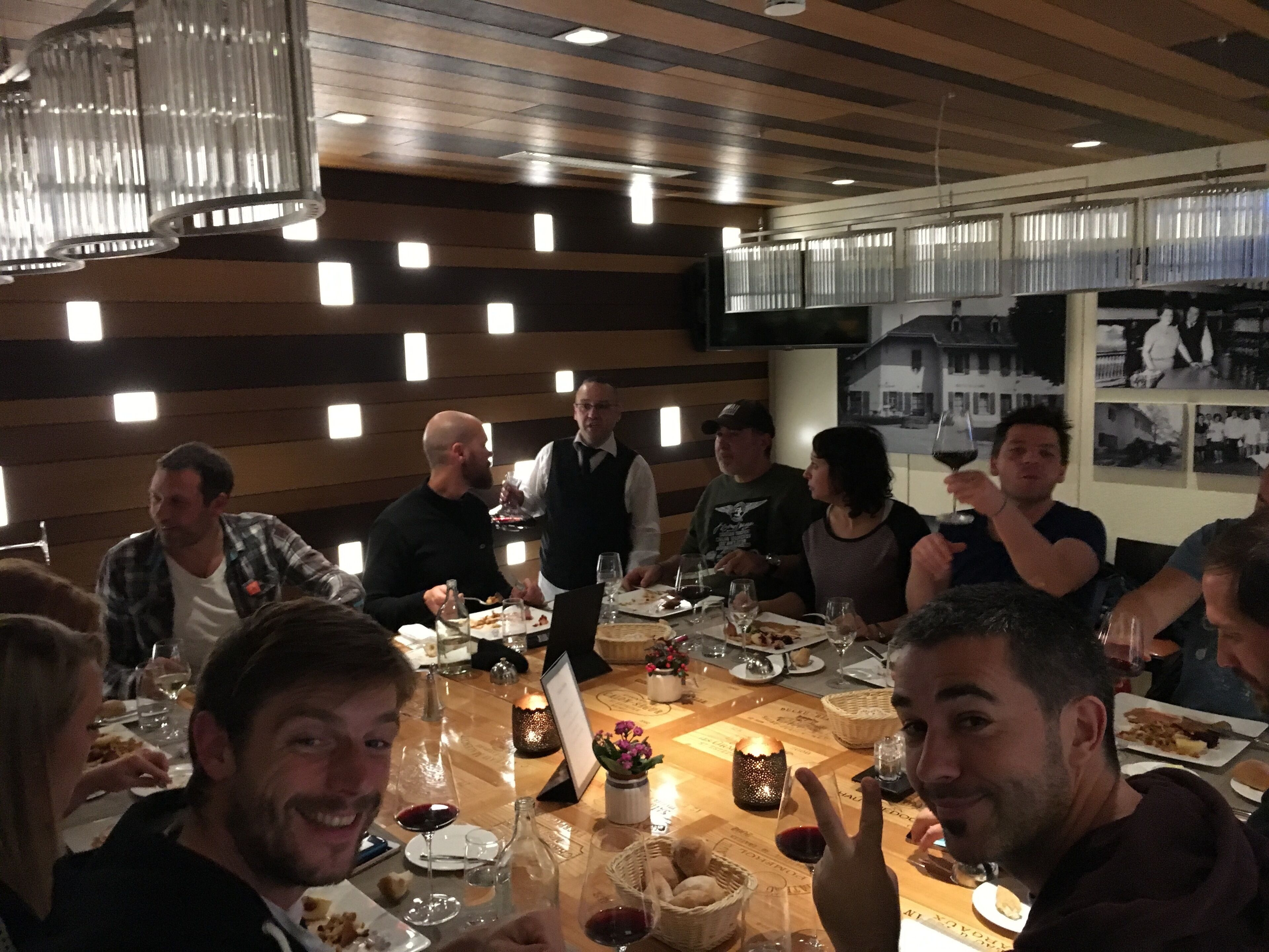 Un grupo de personas cenando en un restaurante con decoración de madera e iluminación moderna.