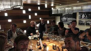 Un gruppo di persone cena in un ristorante con interni in legno e illuminazione moderna.
