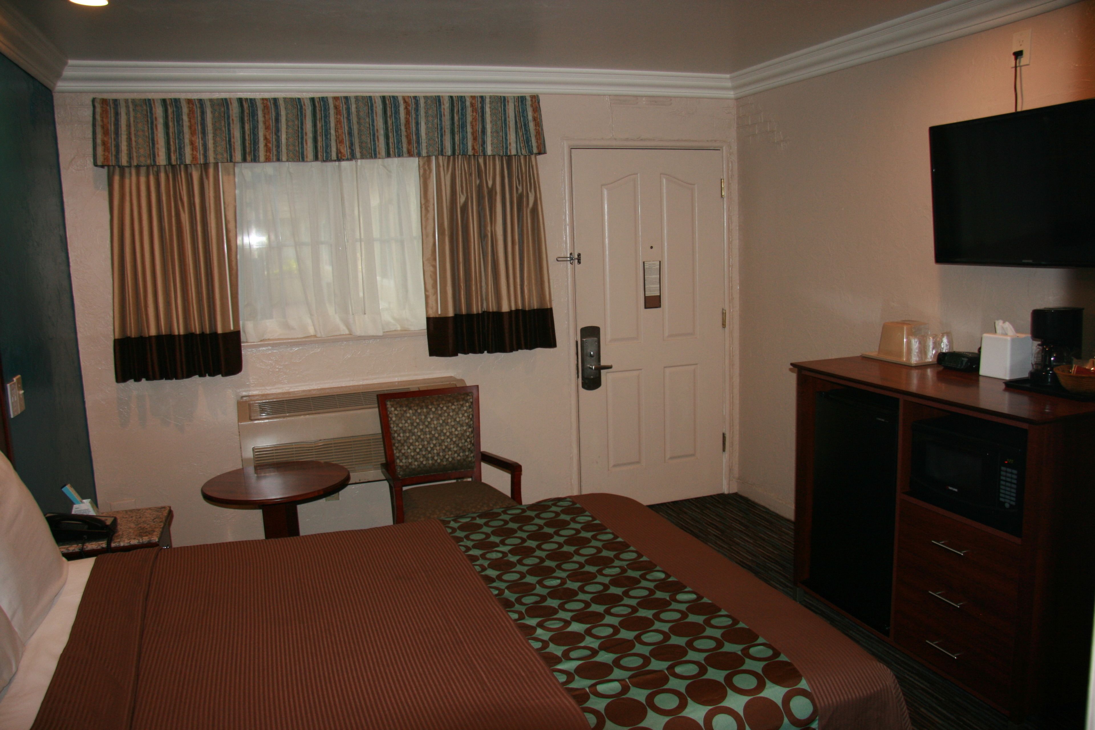 Une chambre d’hôtel équipée d’un lit, d’un bureau, d’une chaise, d’une télévision et d’un mini-bar.