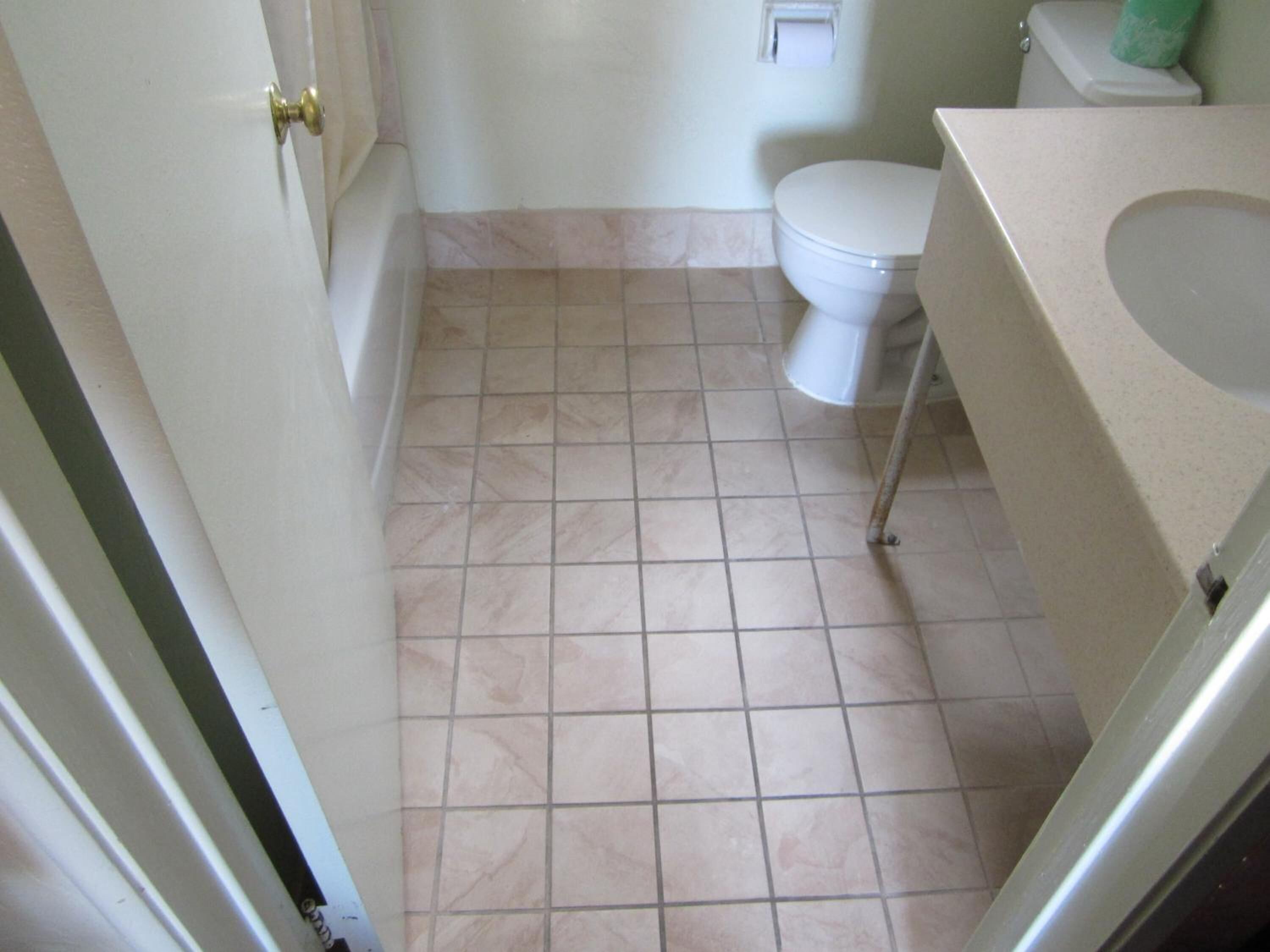 Een badkamer met toilet, wastafel en betegelde vloer.
