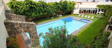 Una piscina al aire libre, sillones reclinables de piscina