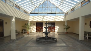 A spacious atrium with a central fountain, high ceilings with skylights, and potted plants. - Hotel Real de Minas San Luis Potosi (San Luis Potosi)