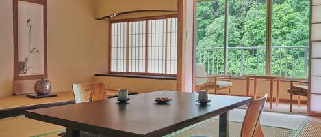 Una habitación japonesa tradicional con suelo de tatami, una mesa baja y puertas correderas shoji.